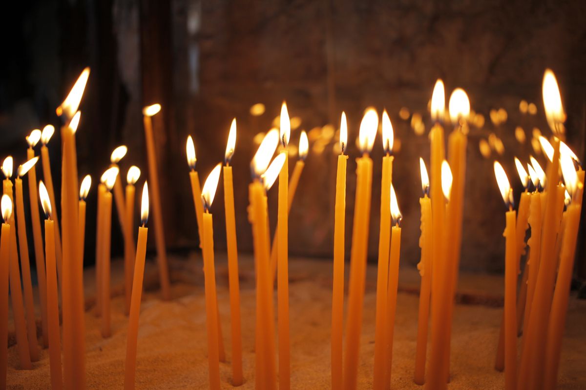 Candele accese in una chiesa, segno della preghiera e della luce dei Santi