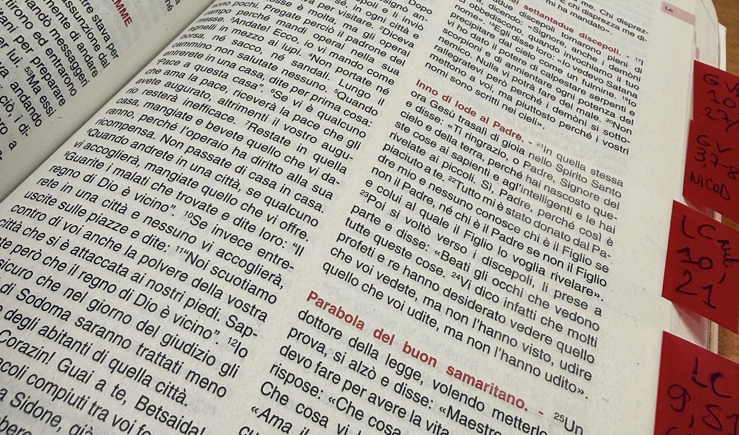 Una Bibbia aperta sul Vangelo di Luca, con segnalibri rossi scritti a mano sui passi della Scuola di Comunità