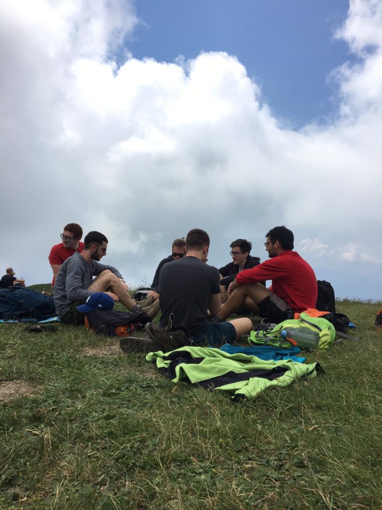 Amici seduti in cerchio sull'erba durante la sosta in quota