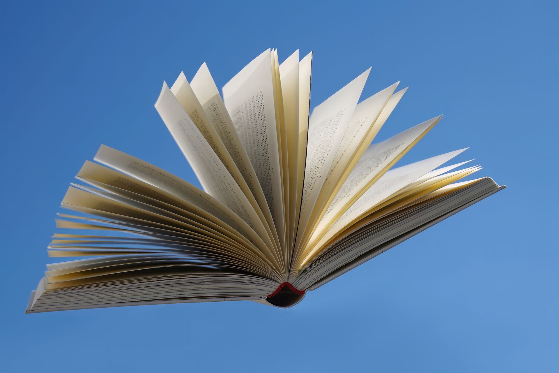 Un libro aperto con le pagine sfogliate contro il cielo azzurro